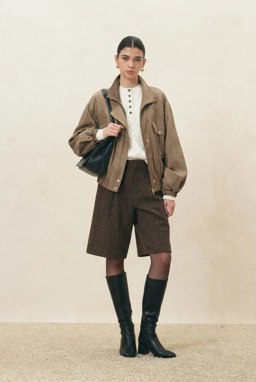 Women's taupe jacket with stand collar and gathered hem, styled with brown shorts and knee high boots